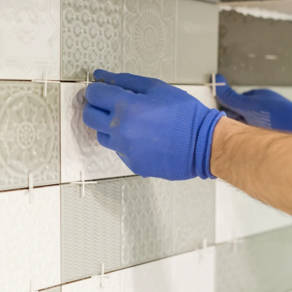 Hands installing a tile backsplash in a modern kitchen