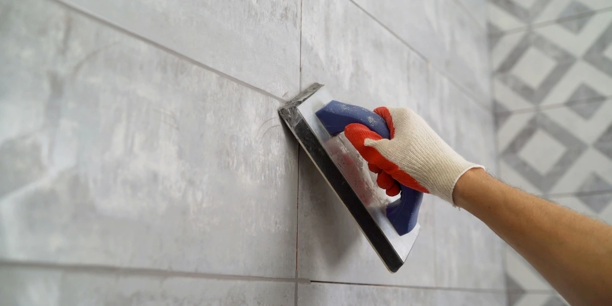 Worker applying grout to newly installed wall tiles